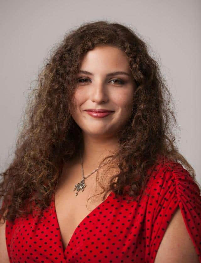 Brittany Elges Editor Brittany Elges wearing a red and black polkadot shirt, smiling at the camera.